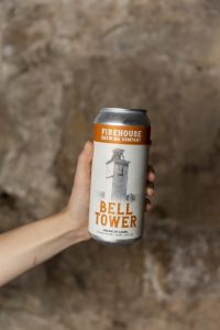 Person holding a can of Bell Tower Lager from Firehouse Brewing Co.